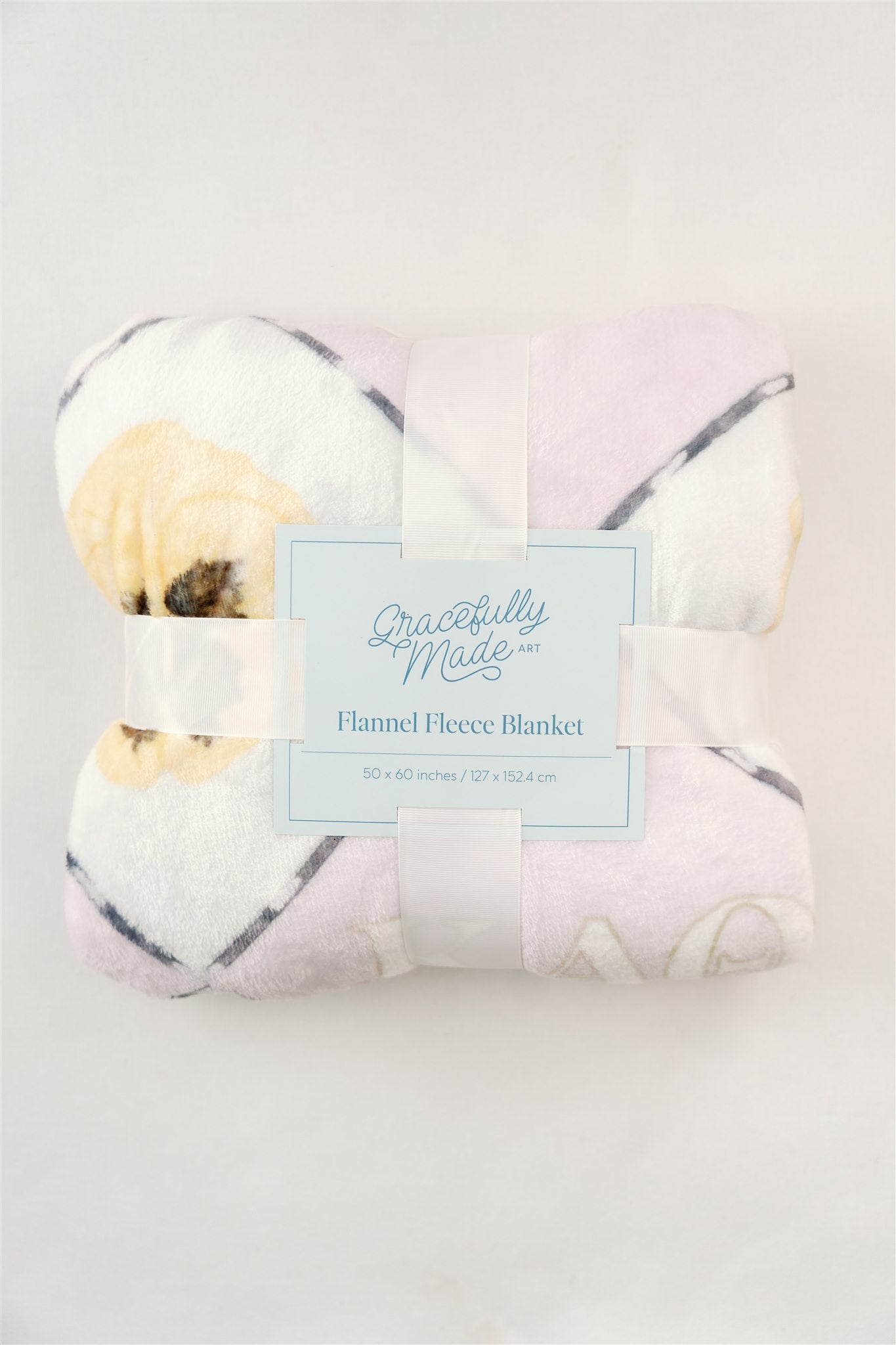 Folded fleece blanket with a Gracefully Made Art brand card and white ribbon.