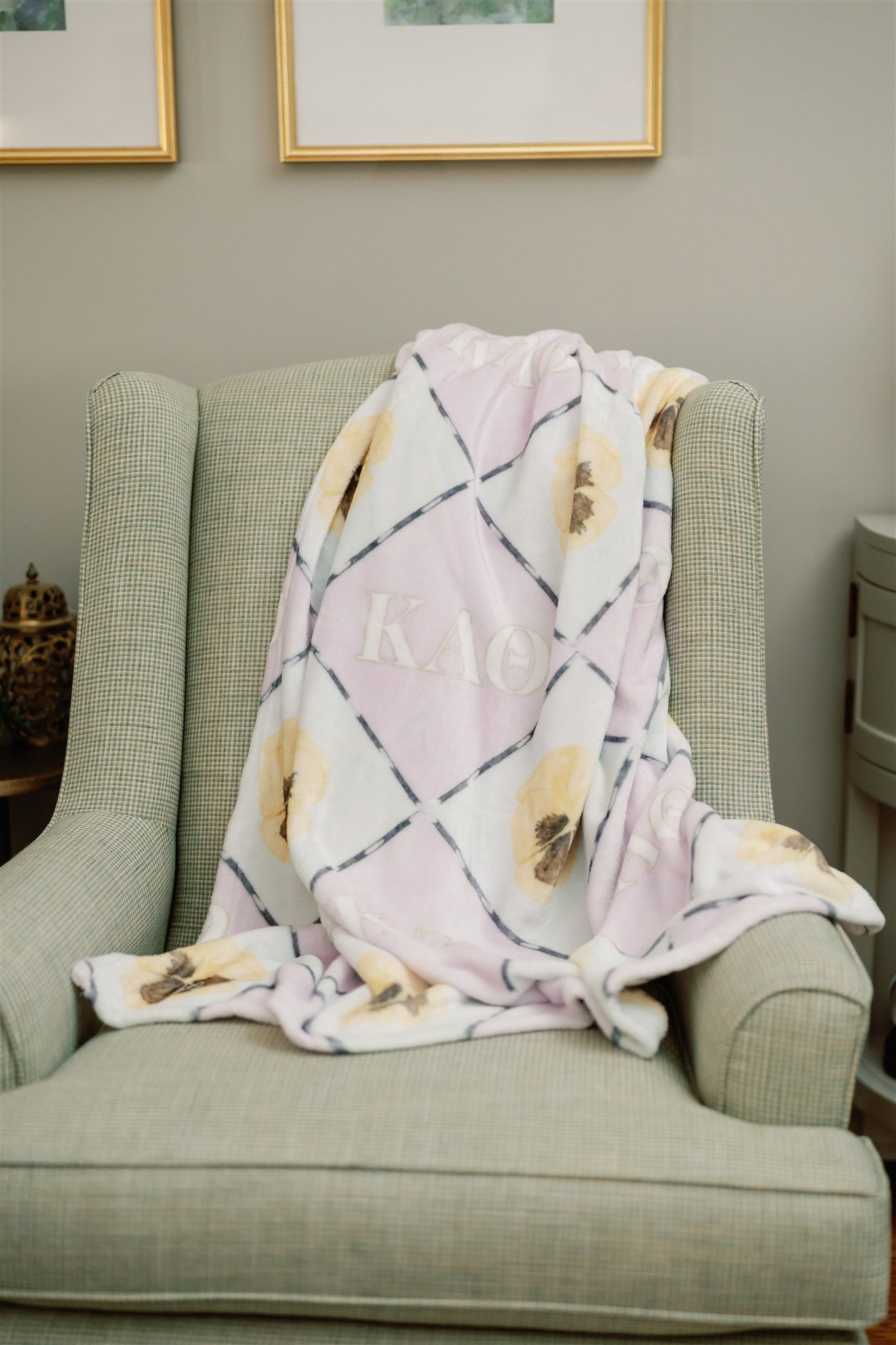 Purple and blue checkered fleece blanket with Kappa Alpha Theta greek letters draped over a chair.