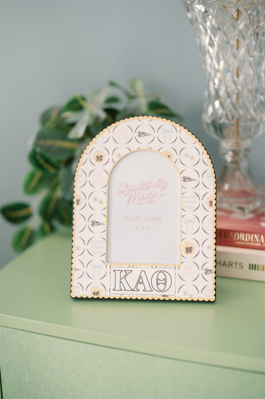 Decorative photo frame with Kappa Alpha Theta pattern and Greek letters on a green dresser.