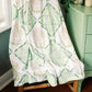 Green and white Kappa Delta patterned blanket draped over a chair in a room with green walls.