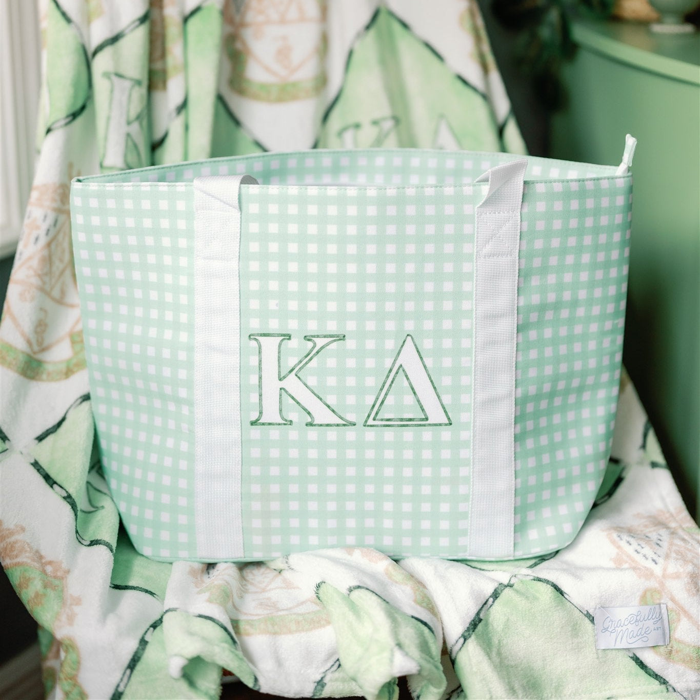 Green checkered bag with 'Kappa Delta' Greek letters on a floral background