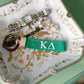 Green keychain with Kappa Delta Greek letters embroidered in white on a jewelry dish.