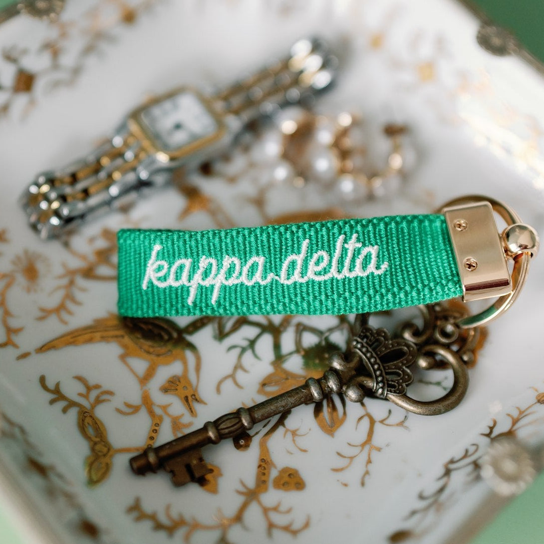 Green 'kappa delta' keychain with vintage keys on a decorative surface