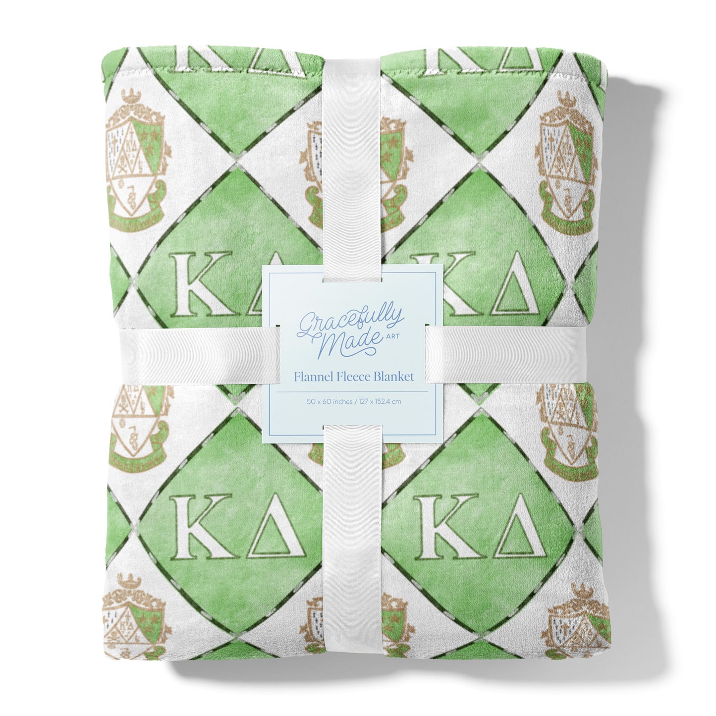 Green and white patterned fleece blanket with 'Kappa Delta' symbols, tied with a ribbon, on a white background.