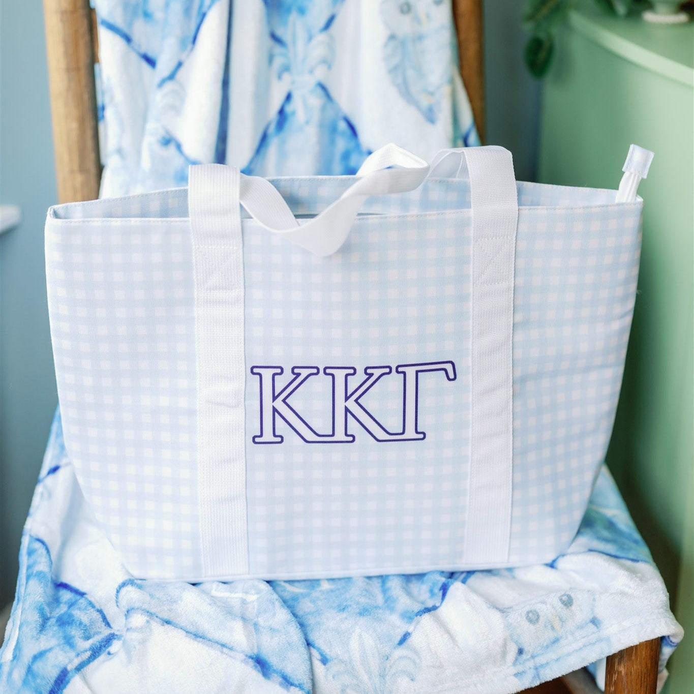Tote bag with Kappa Kappa Gamma Greek letters on a chair with blue and white patterned blanket