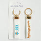 Front and back of a white keychain with KKG and Kappa Kappa Gamma embroidered on it with branded packaging.