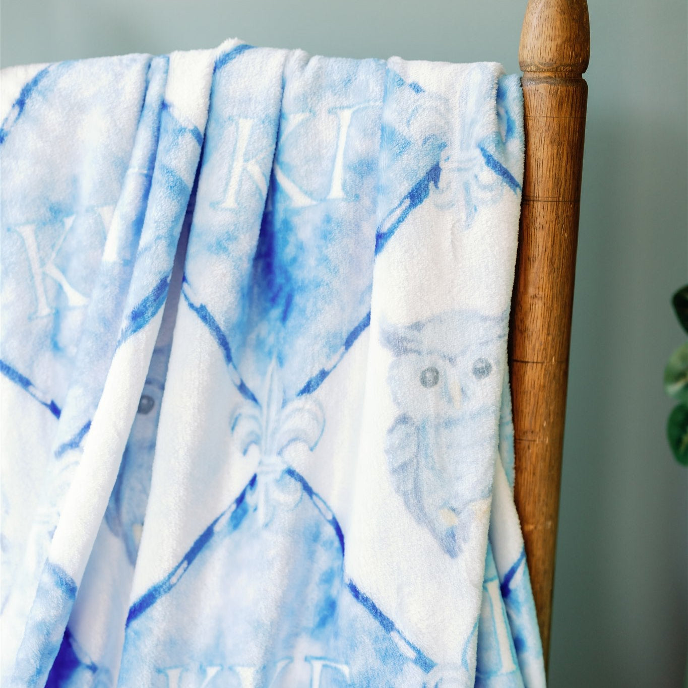Blue and white KKG fleece blanket draped over a wooden chair 