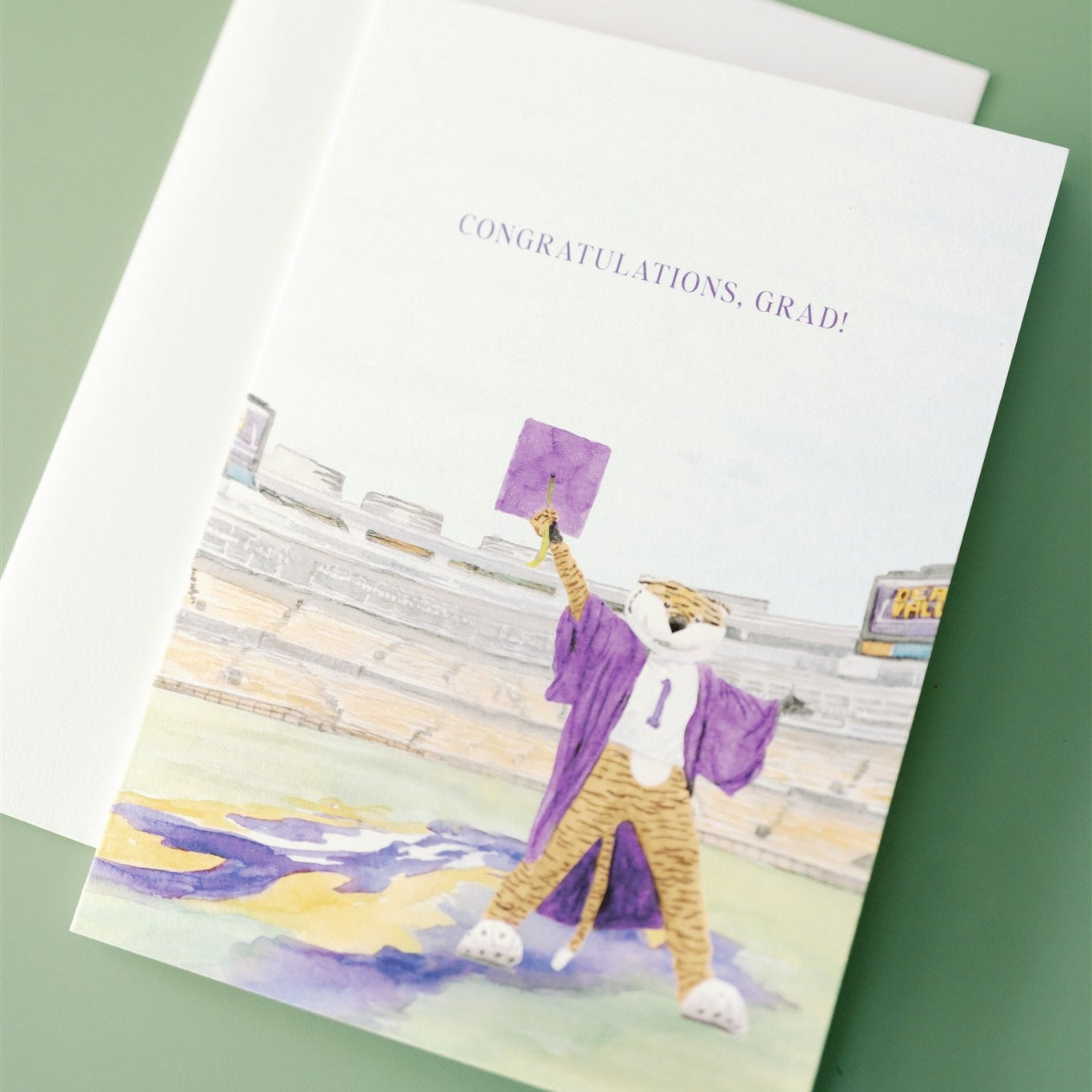 Graduation-themed card with LSU's mascot in a cap and gown on a green background