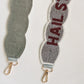 A close up of the bottom of a light grey beaded purse strap with a white beaded, scalloped border, and maroon lettering displaying 'Hail State' and the flip side of the strap showing a felt backing.