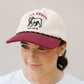 Person wearing a white and maroon cap with a bulldog logo on a plain background