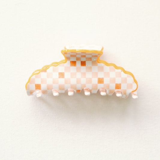 Orange checkered hair clip with scalloped edge on a white background