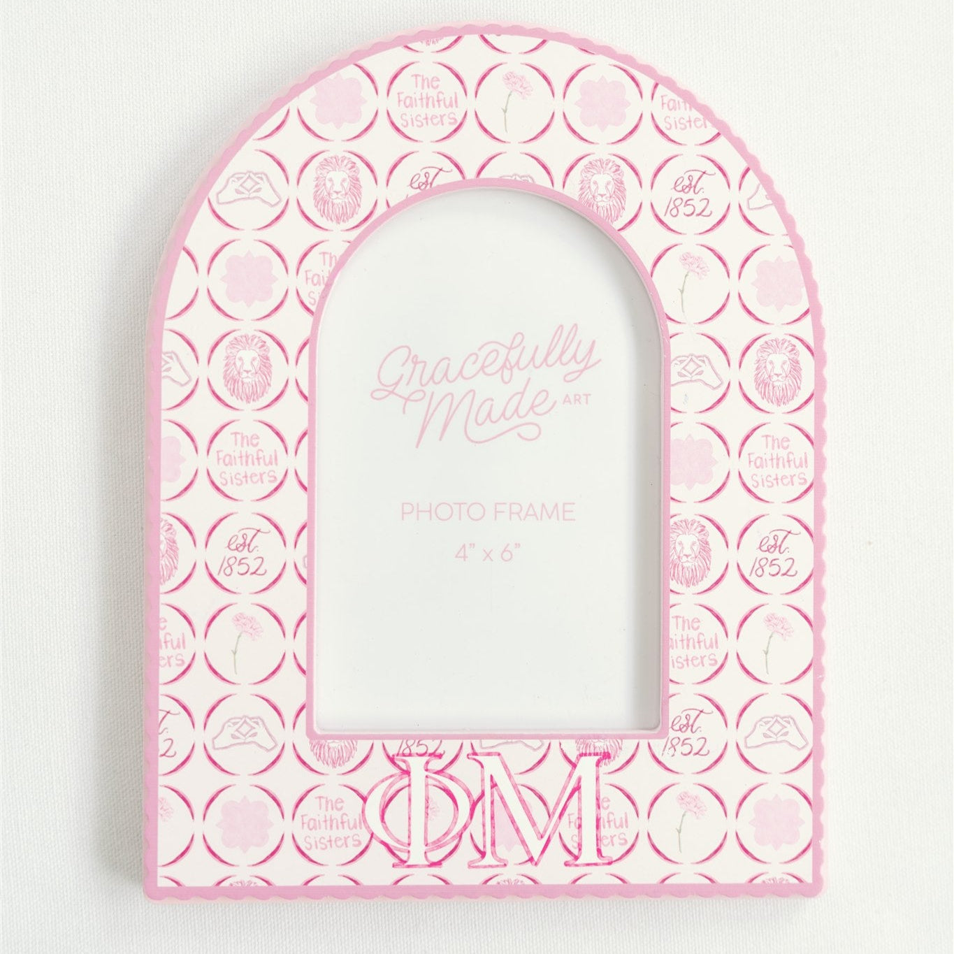 Pink arch-shaped picture frame with circular patterns and Phi Mu Greek letters on a white background