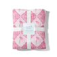 Pink quilt with floral patterns and Phi Mu Greek letters, tied with a white ribbon on a white background.