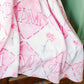 Pink and white blanket with Phi Mu Greek letter symbols and flower draped over a chair.