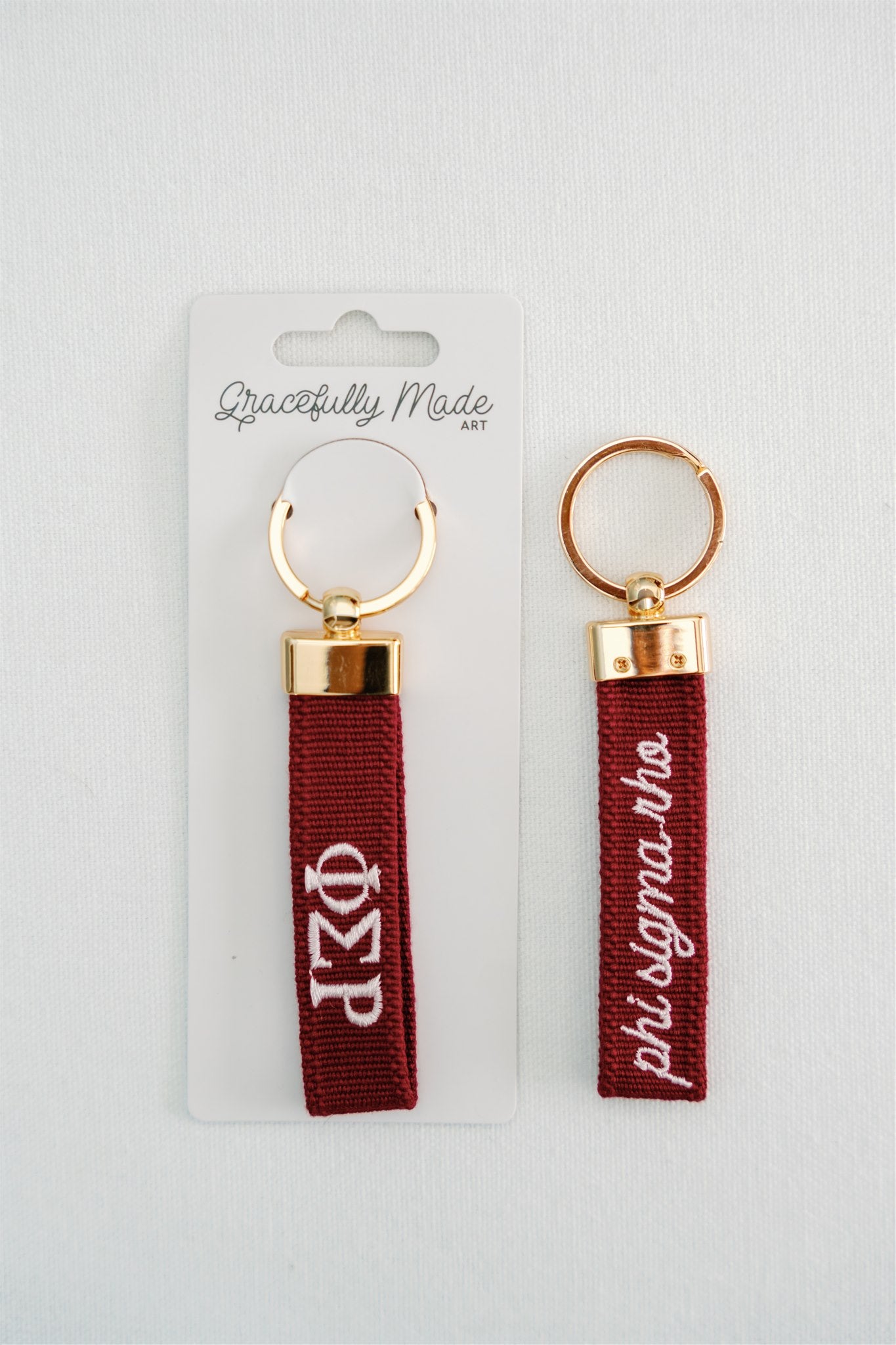 Front and back of the red keychain with Phi Sigma Rho embroidered on it in white.