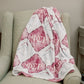 Red and white blanket with Phi Sigma Rho Greek letters draped over a chair in a room.