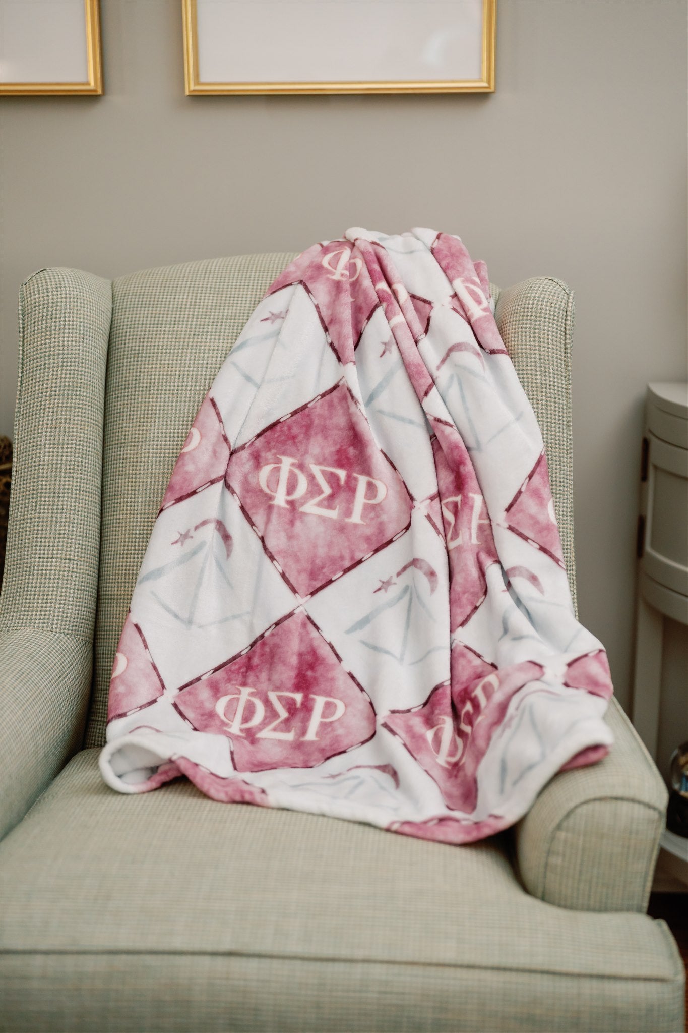 Red and white blanket with Phi Sigma Rho Greek letters draped over a chair in a room.