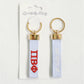 Pi Beta Phi keychain with gold loops and white ribbons featuring red text on a white background.