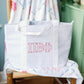 Grey gingham tote bag with Pi Beta Phi Greek letters on a wooden chair against a light green wall.