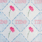 Embroidered fabric with pink flowers and 'ΠΒΦ' letters on a blue checkered background.