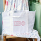 Gray checkered tote bag with white straps and Pi Beta Phi Greek letters propped on a chair