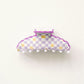 Checkered hair clip with purple border on a white background