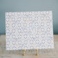 Decorative art print with circular designs and Sigma Delta Tau Greek letters on a stand against a blue background.