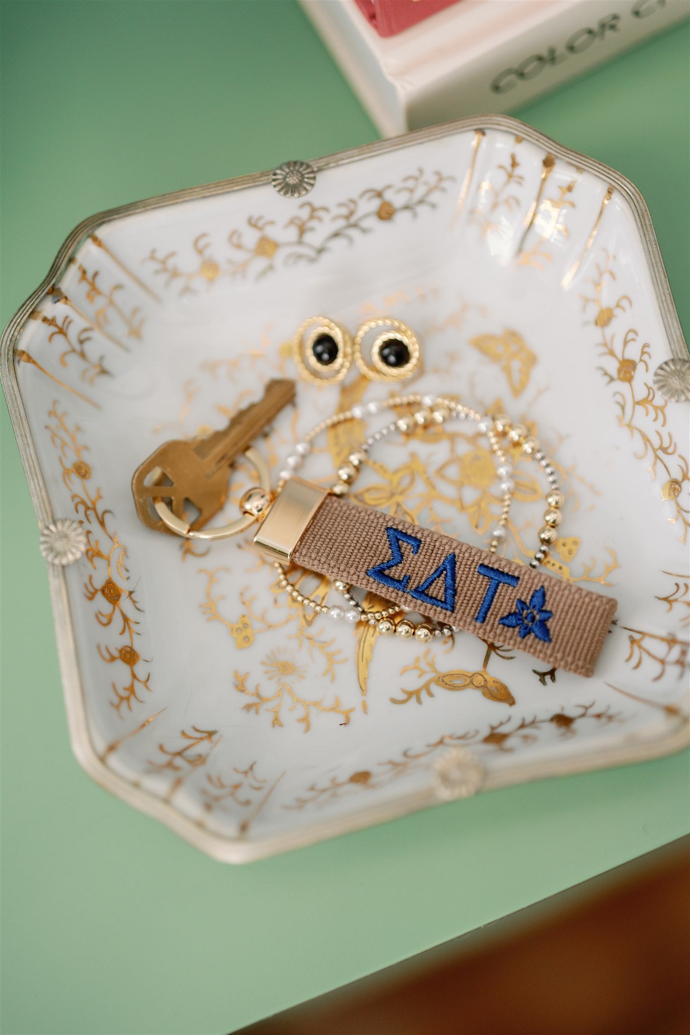 Keychain with Sigma Delta Tau Greek letters embroidered on a decorative jewelry dish.