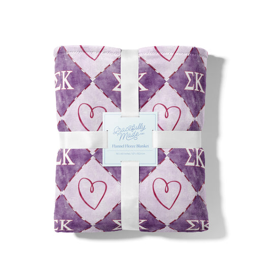 Purple checkered blanket with heart and Sigma Kappa Greek letter pattern.