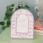 Decorative photo frame with pink and white design and Sigma Kappa Greek letters on a green dresser.