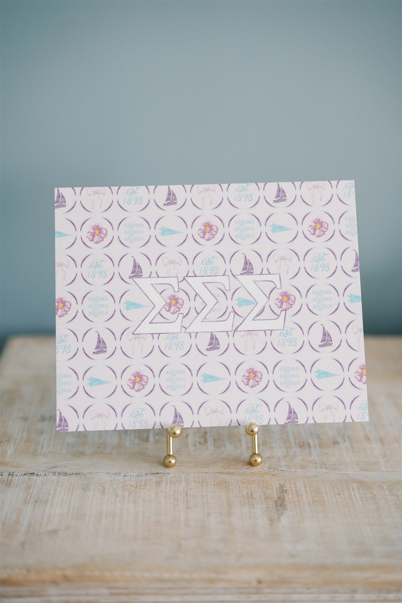 Decorative art print with geometric pattern  and Tri Sigma Greek letters on a stand against a gray background