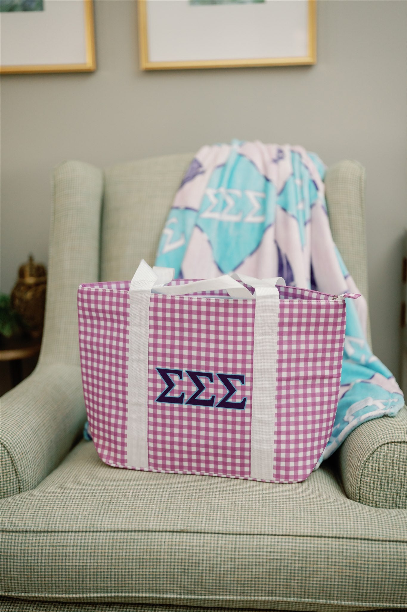 Purple gingham tote bag with blue Tri Sigma Greek letters propped on a green chair