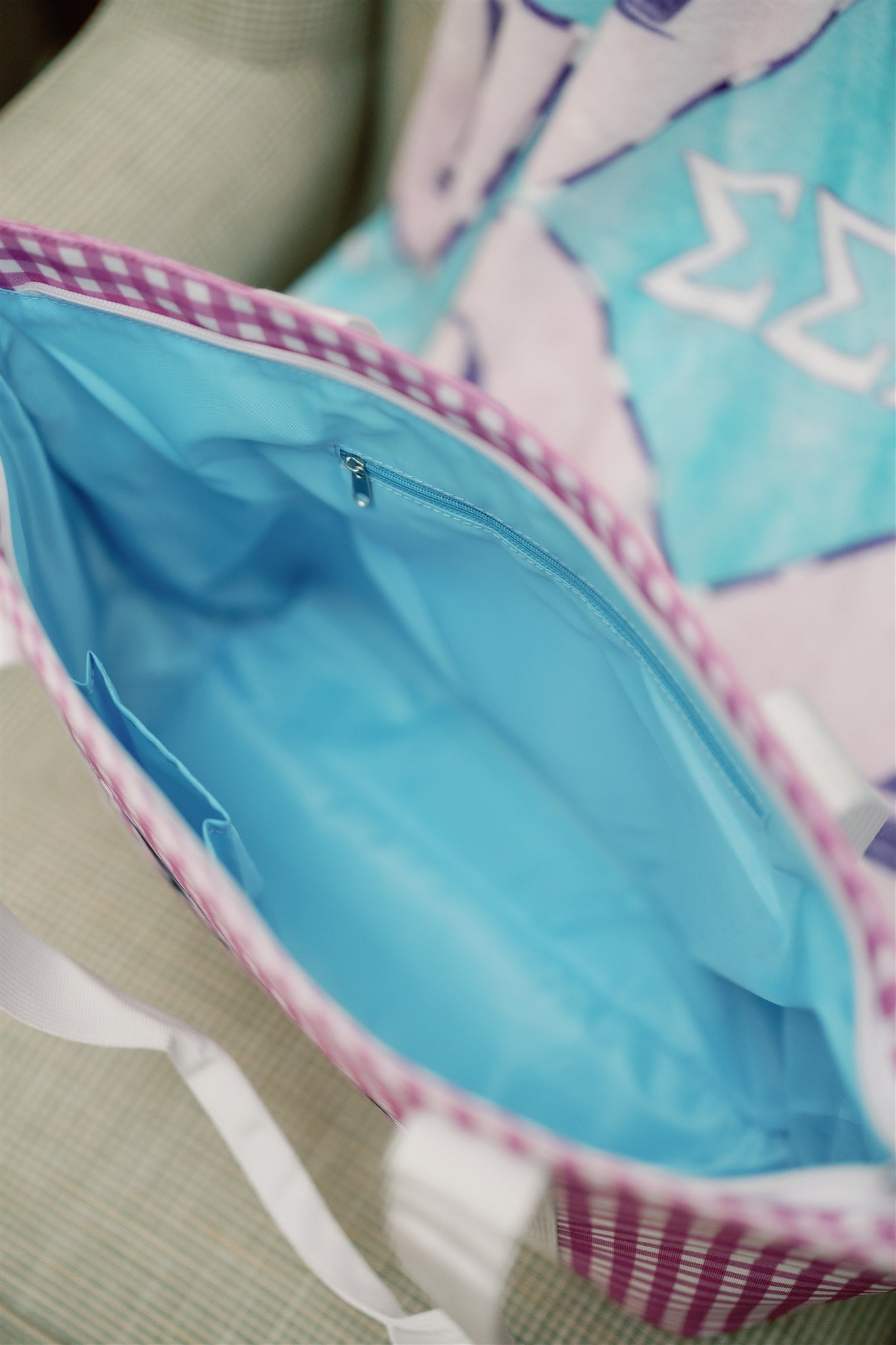 Close up of the Tri Sigma tote bag's bright blue interior liner and zipper pocket.