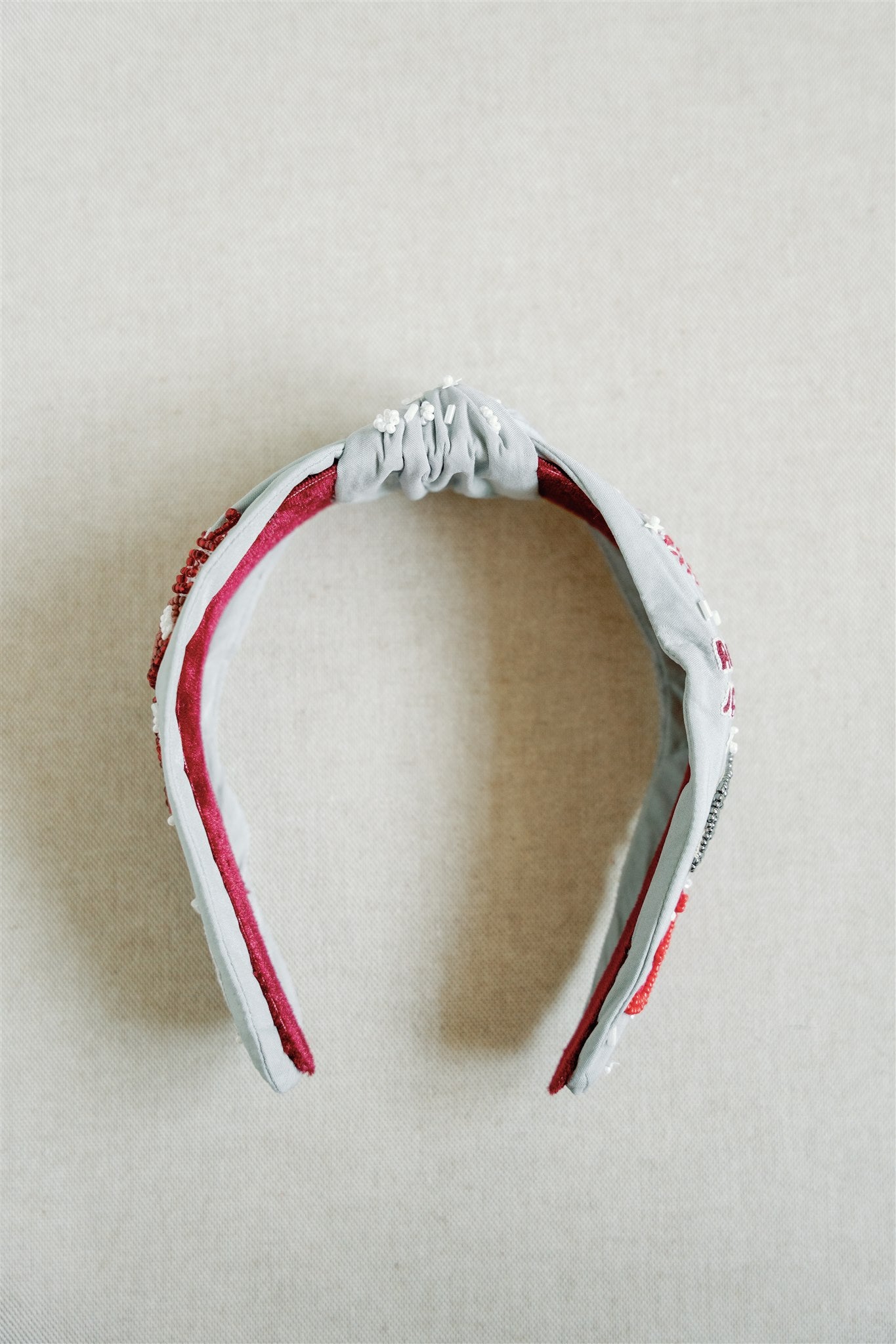 Light grey headband with red and white beaded University of Alabama symbols.