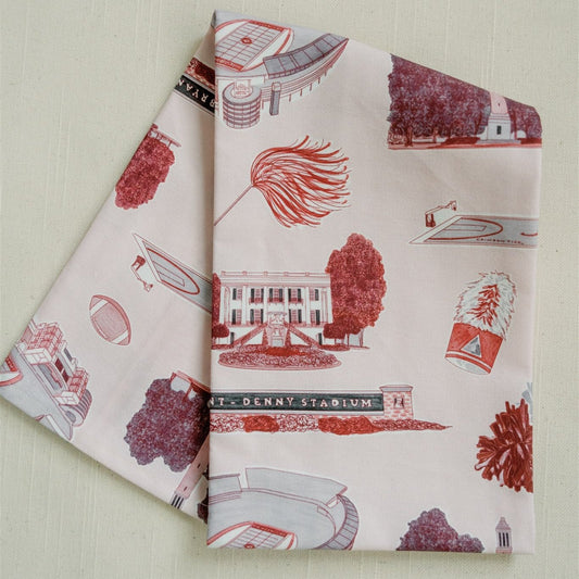 Light red tea towel with University of Alabama symbols. 
