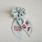 Light grey scrunchie with beaded University of Alabama symbols on the ribbons.