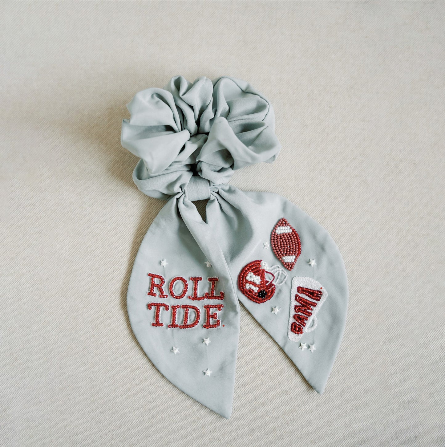 Light grey scrunchie with beaded University of Alabama symbols on the ribbons.