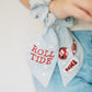 Light grey scrunchie with beaded University of Alabama symbols on the ribbons.