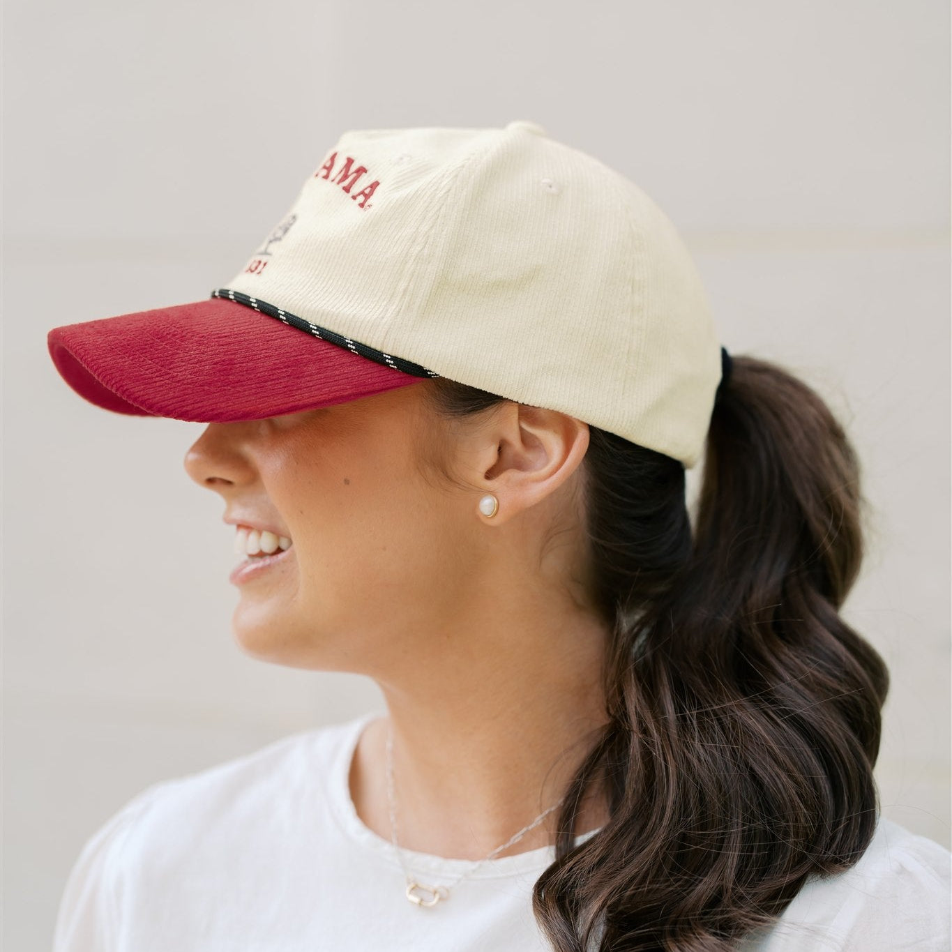 Woman wearing a beige cap with a red brim and 'Alabama' text on a plain background