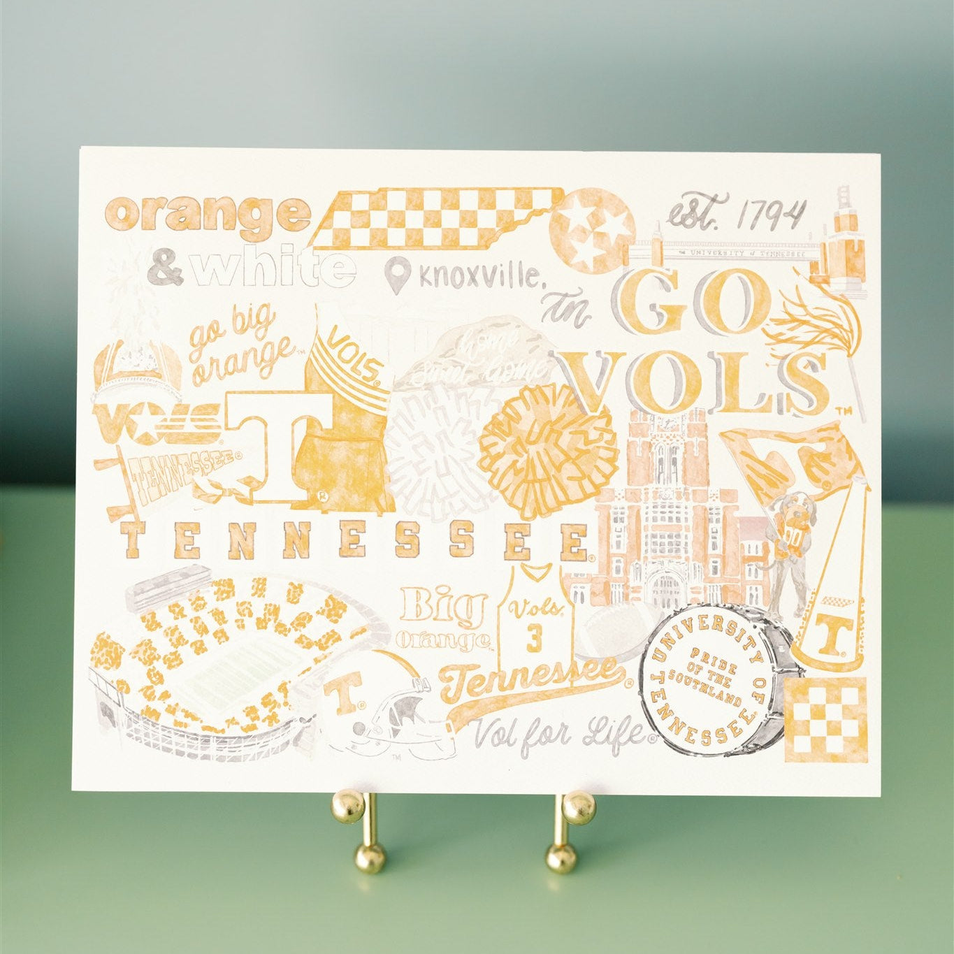 Decorative poster with 'GO VOLS' and other text on a stand on a green dresser