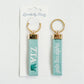 Front and back of Zeta keychain with Gracefully Made Art branded packaging. 