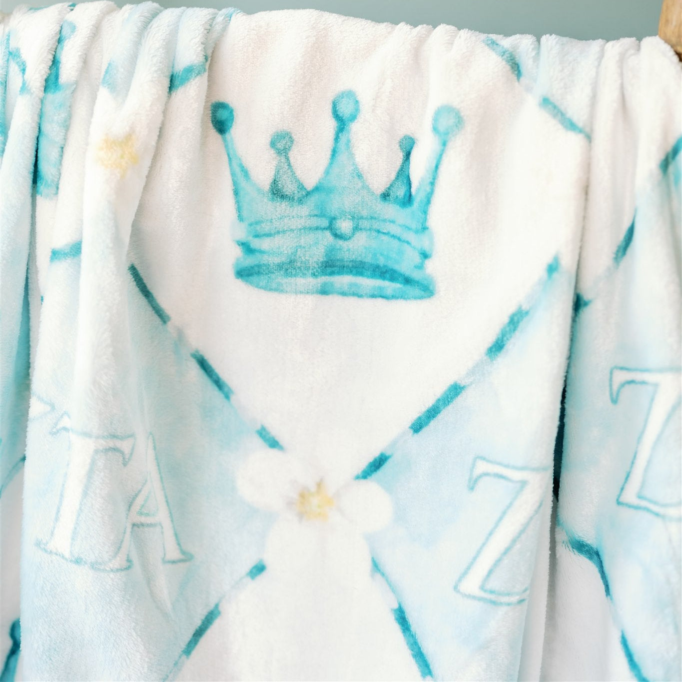 Blue checkered fleece blanket with a crown and ZTA Greek letters on it.